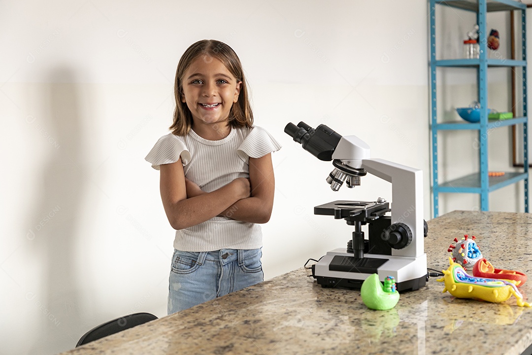 Menina fofa de braços cruzados na frente de um microscópio