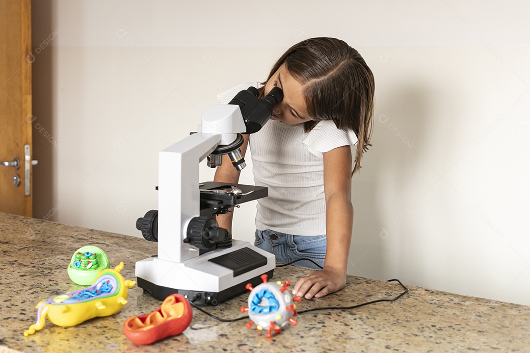 Criança fofa olhando através de um microscópio