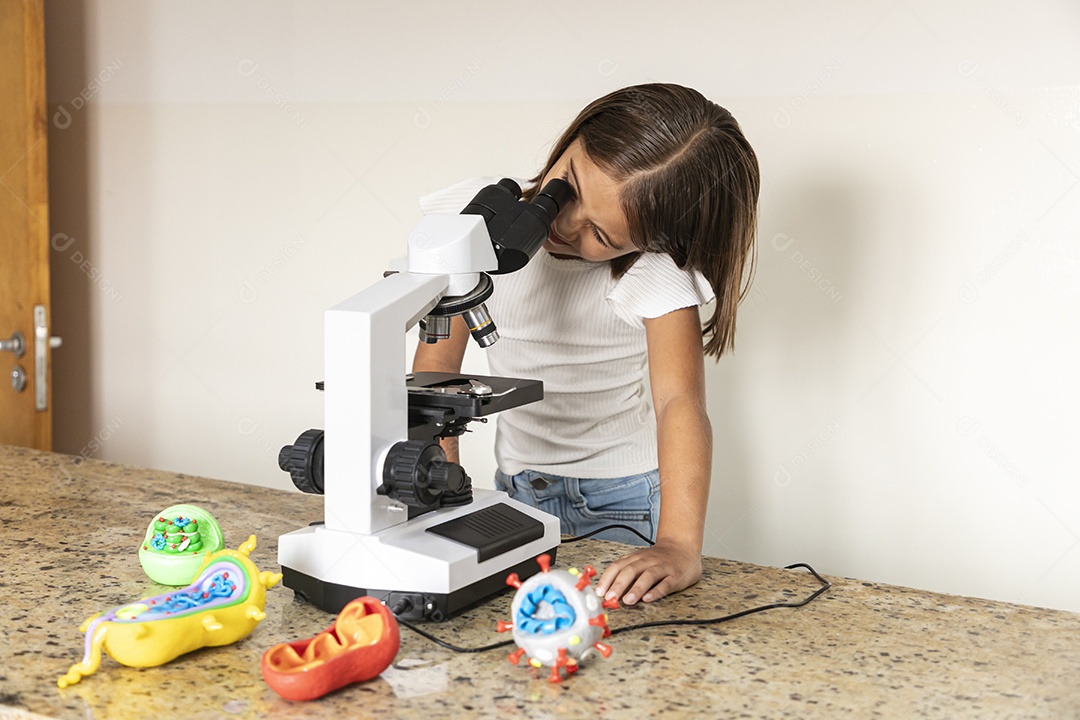 Linda menina olhando através de um microscópio