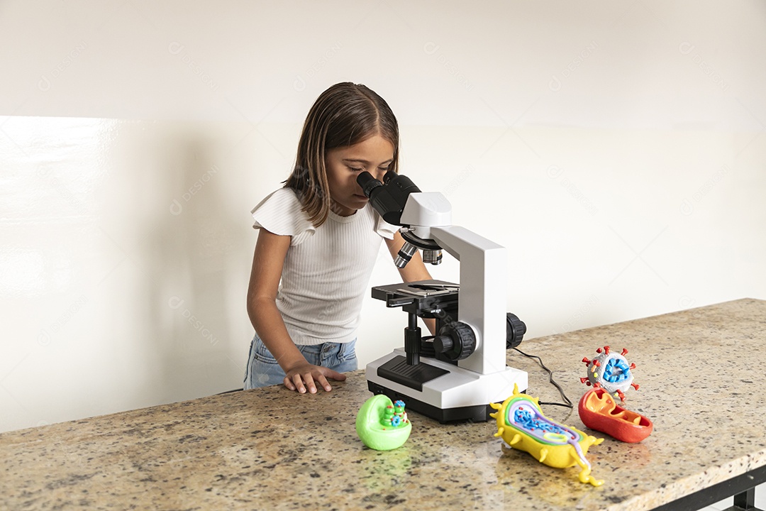 Garotinha fofa olhando através de um microscópio