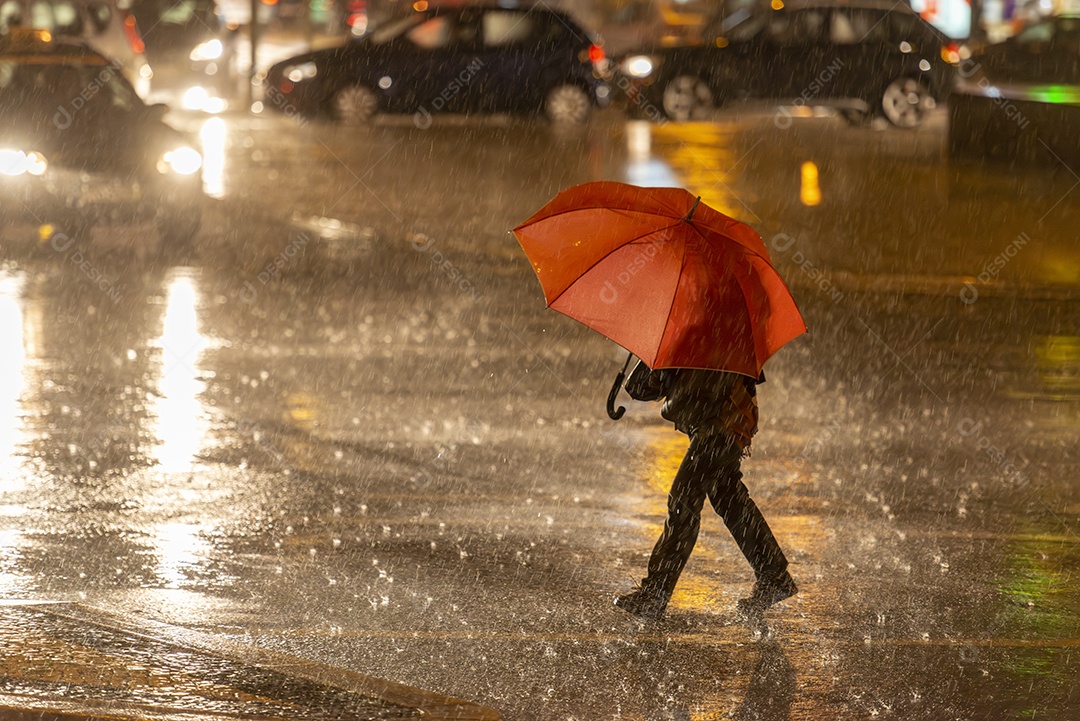 Mulher segurando um guarda chuva colorido durante uma forte tempestade noturna