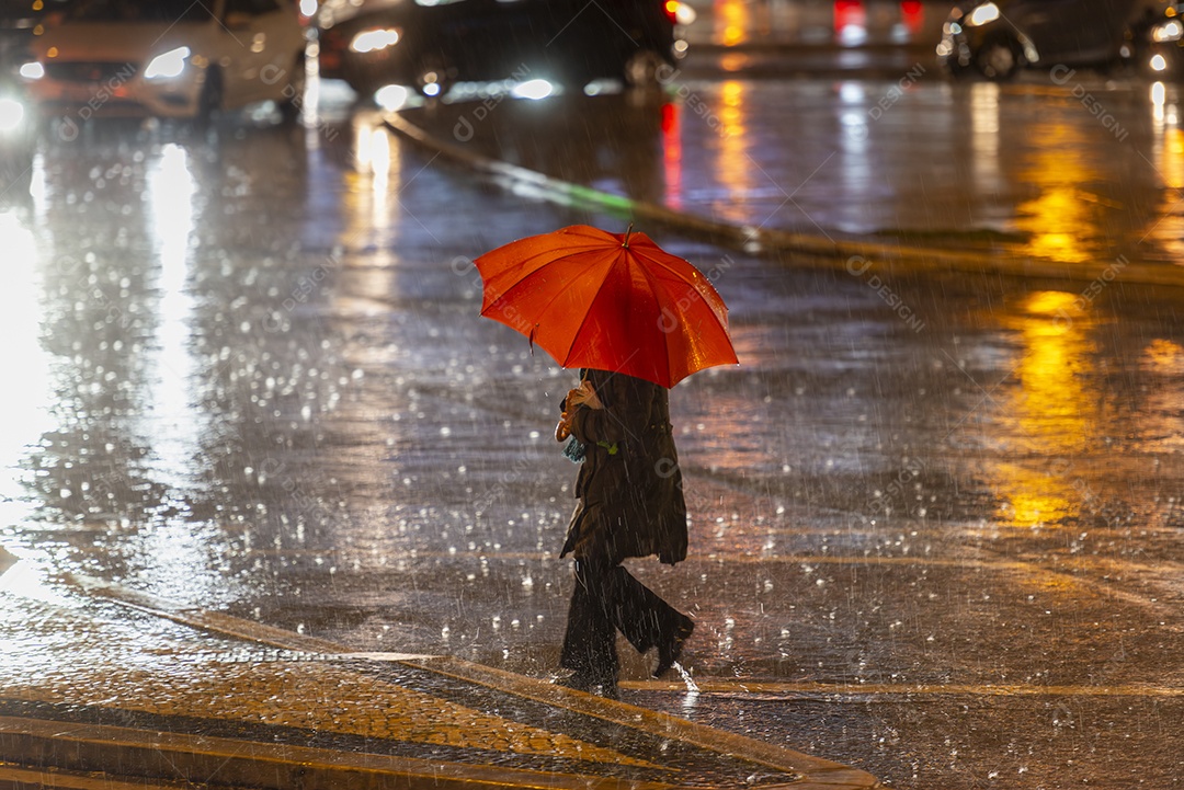 Mulher atravessando a rua segurando um guarda chuva