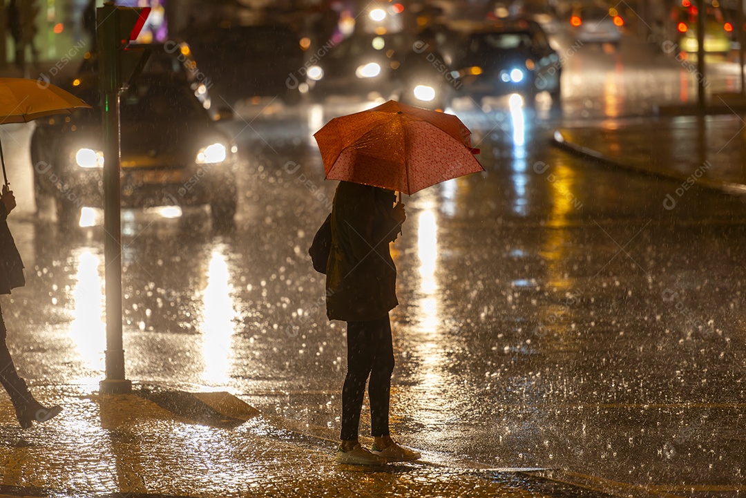 Mulher atravessando a rua segurando um guarda chuva