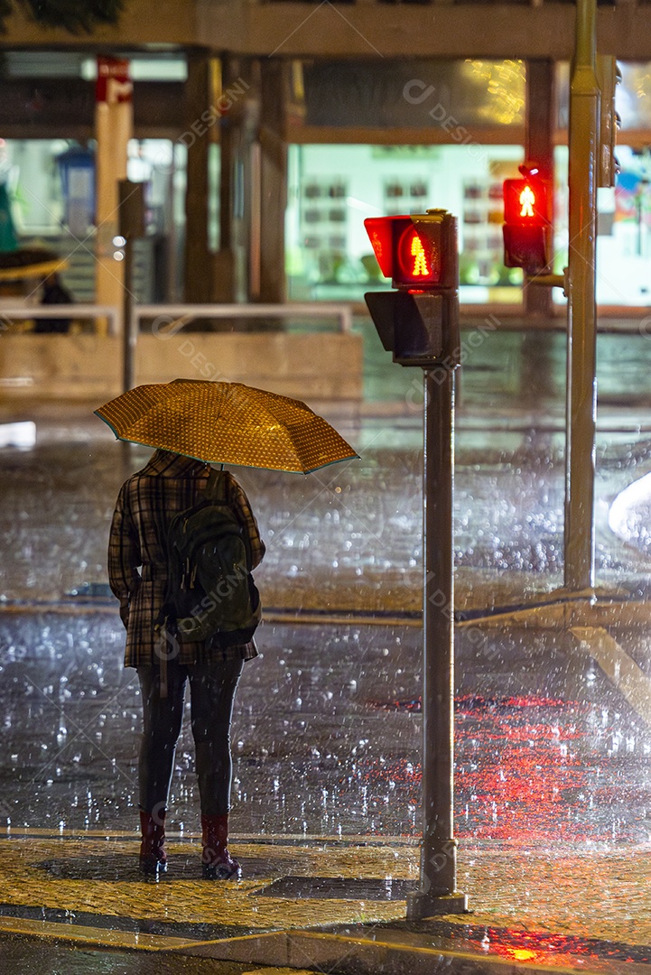 Mulher atravessando a rua segurando um guarda chuva