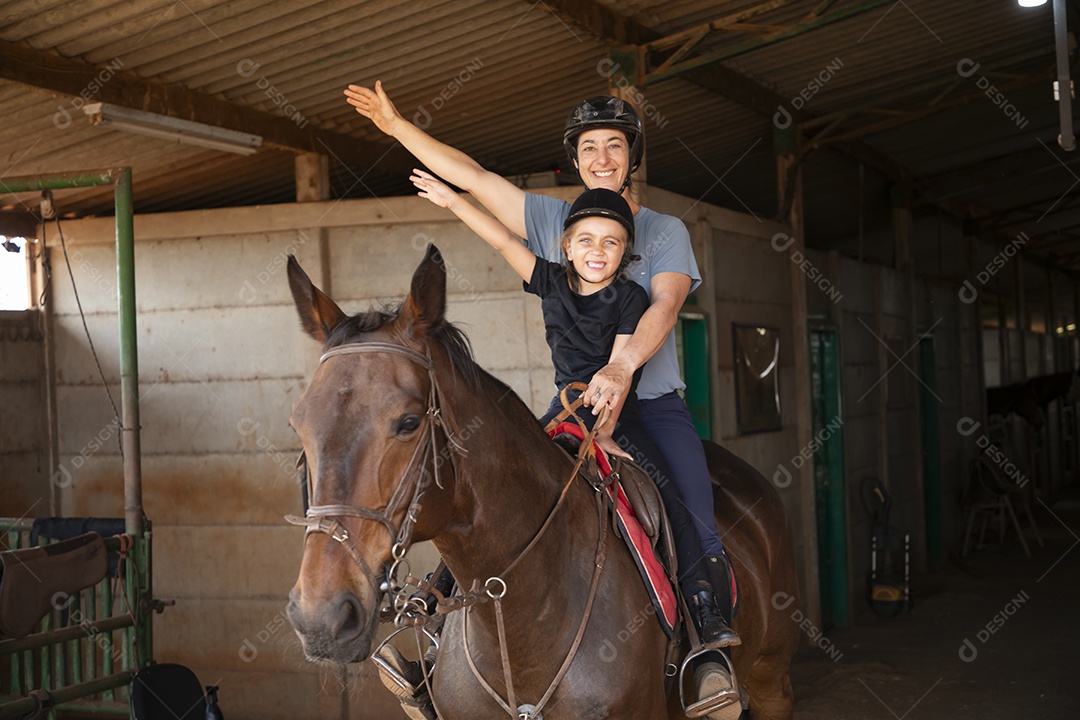 Treinadora se divertindo ao ensinar hipismo para garotinha
