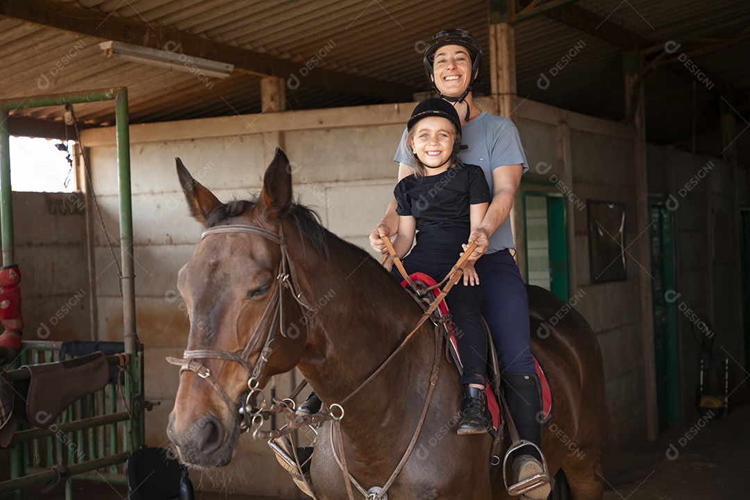 Treinadora se divertindo ao ensinar hipismo para garotinha