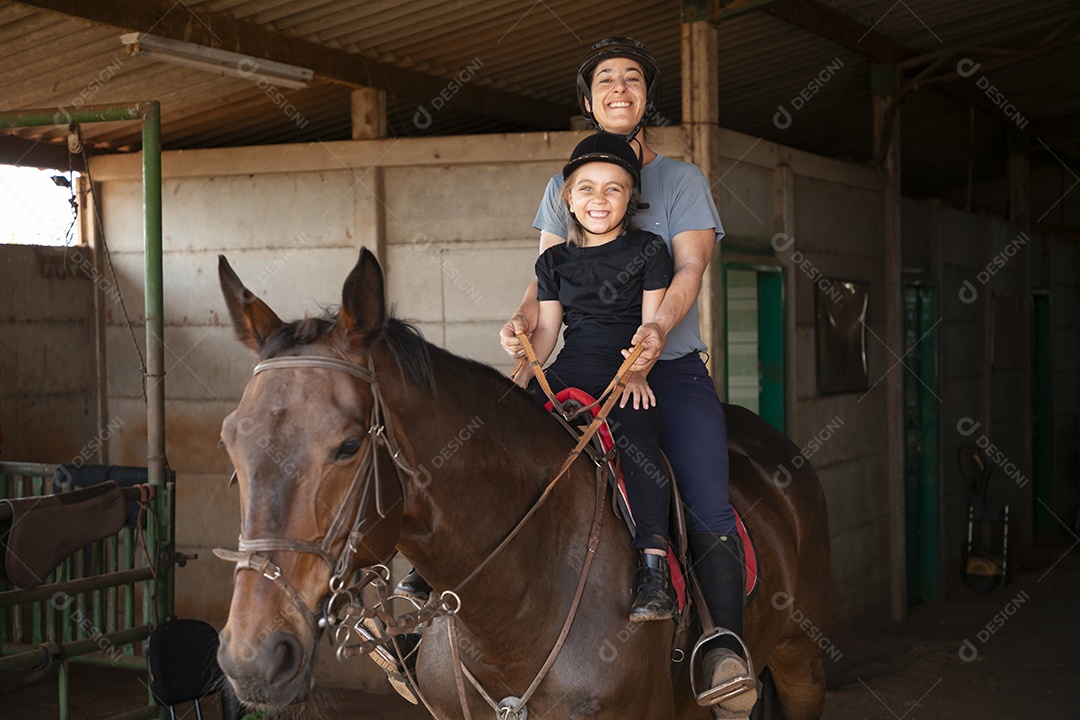 Treinadora se divertindo ao ensinar hipismo para garotinha