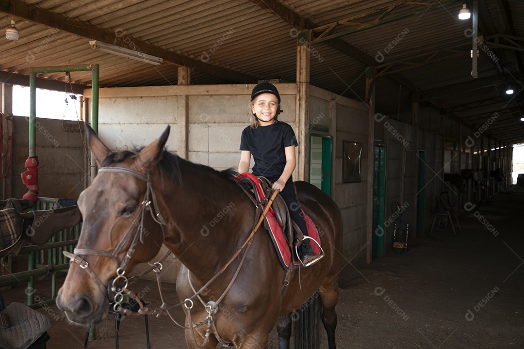 Garota feliz montada a um cavalo para aula de hipismo