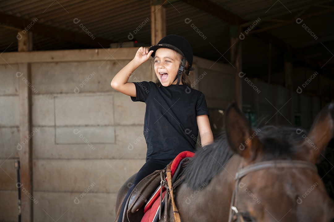 Garotinha feliz montada em um cavalo para aula de hipismo