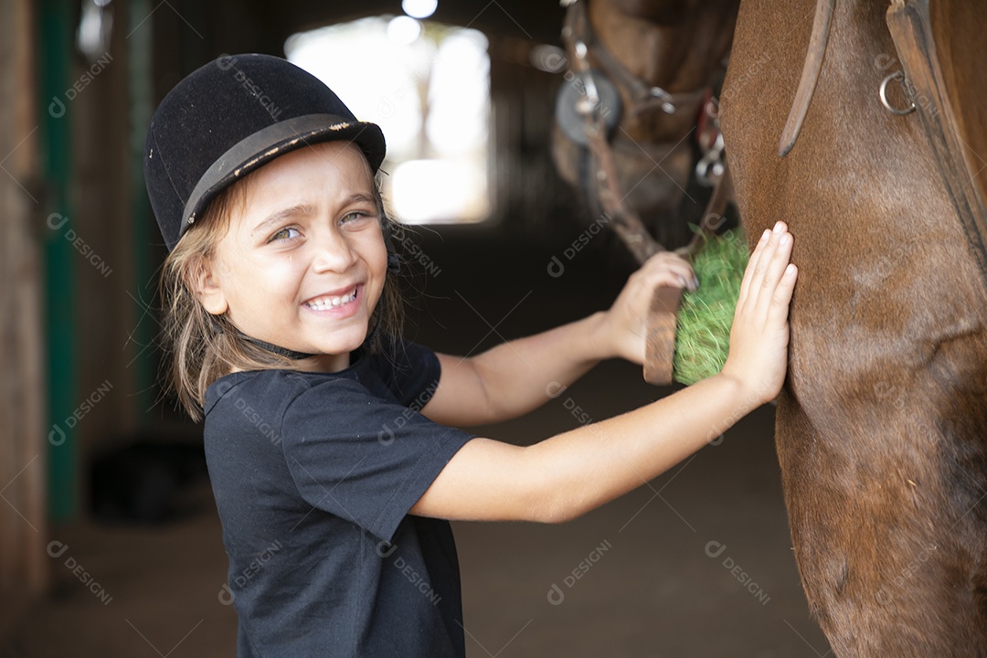 Menina linda escovando o cavalo de treino
