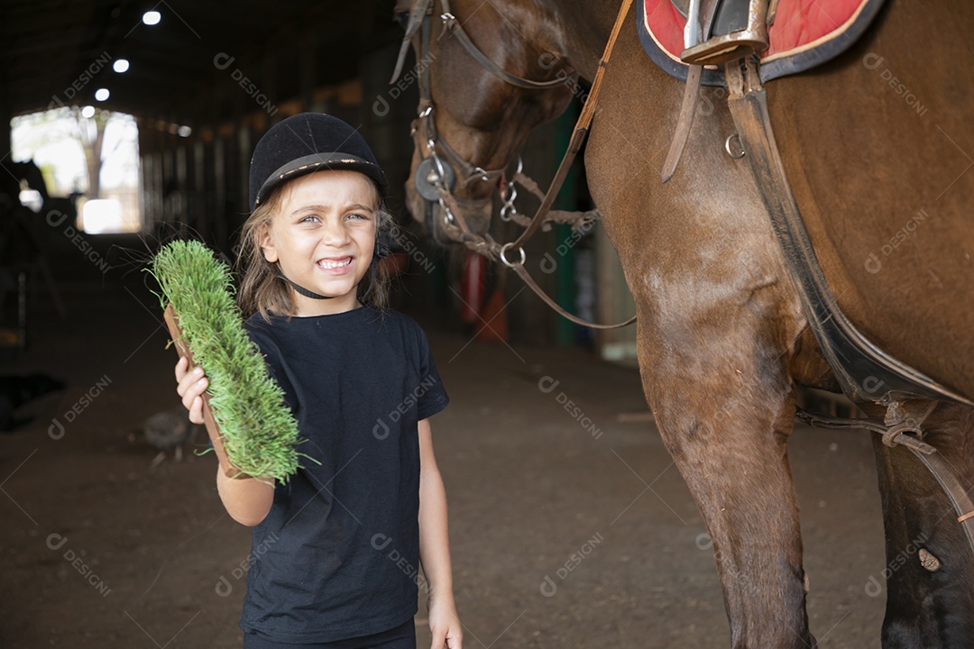 Garotinha linda com escova na mão para cavalo