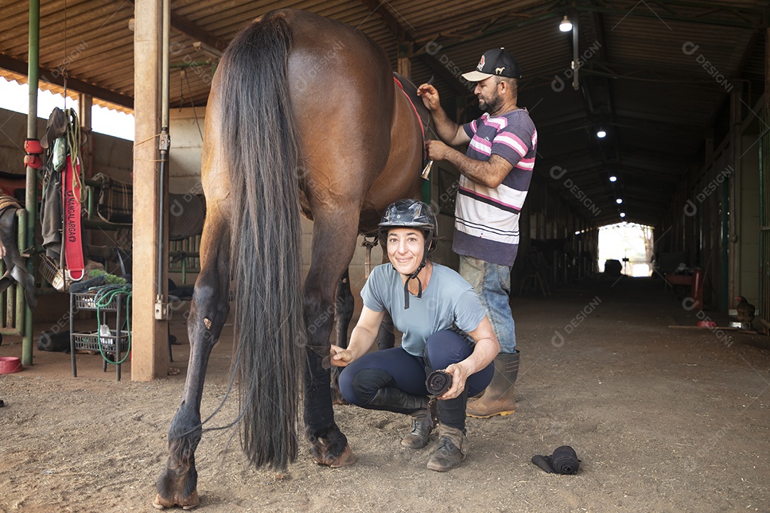 Homem e montadora cuidando de cavalo para treino