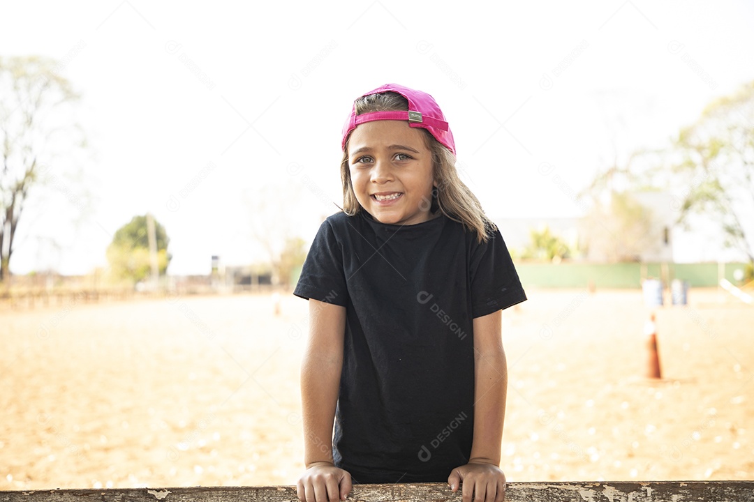 Menina com boné na cabeça se divertindo em treino de hipismo