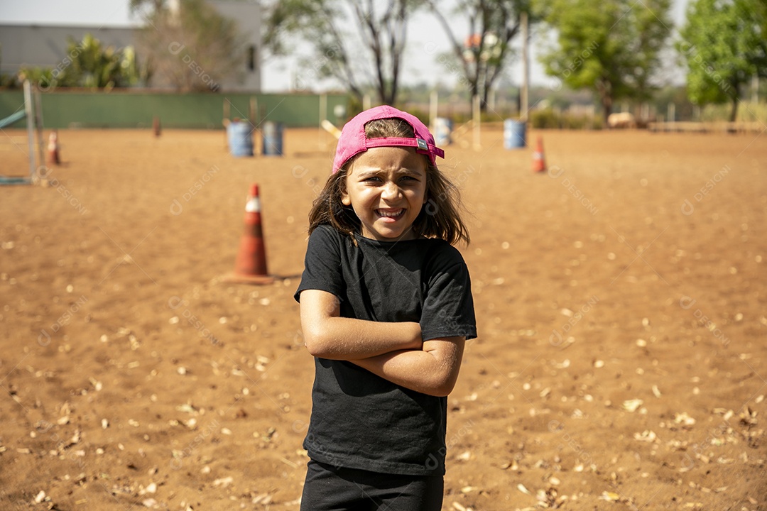 Garotinha de boné em um ara para treino de hipismo