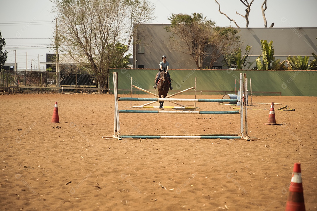 Mulher treinando hipismo com obstáculos com seu cavalo
