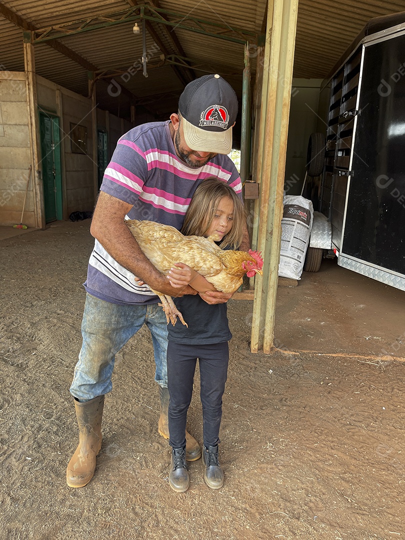 Garotinha feliz com sua galinha e um homem ajudando ela