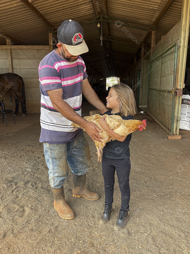 Homem ajudando a menina a segurara a galinha