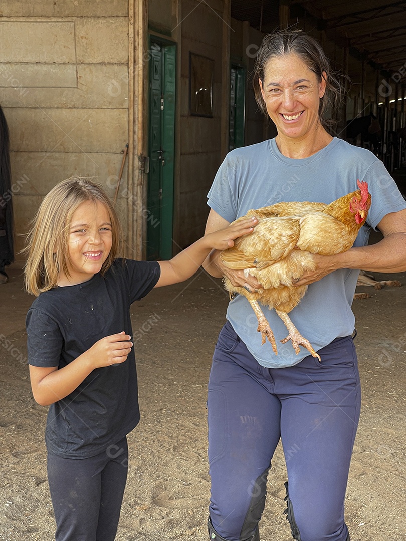 Mulher e uma criança com galinha nas mãos
