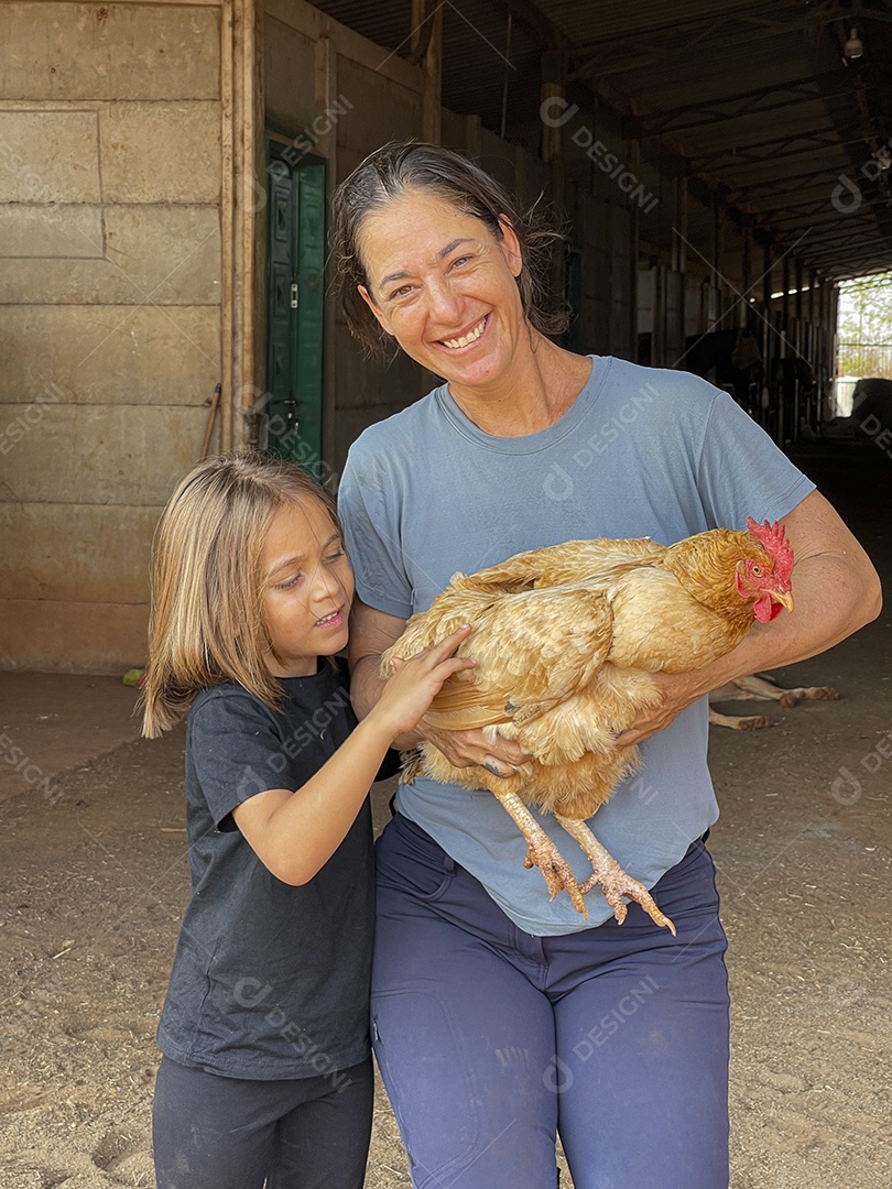Mulher e uma criança com galinha nas mãos