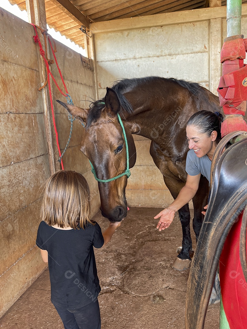 Duas garotas dando comida a um cavalo