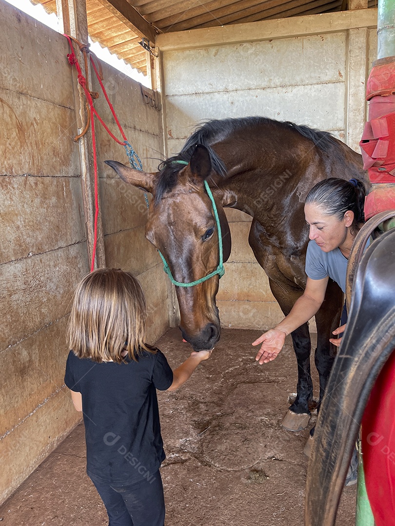 Mulher e uma criança dando comida a um cavalo
