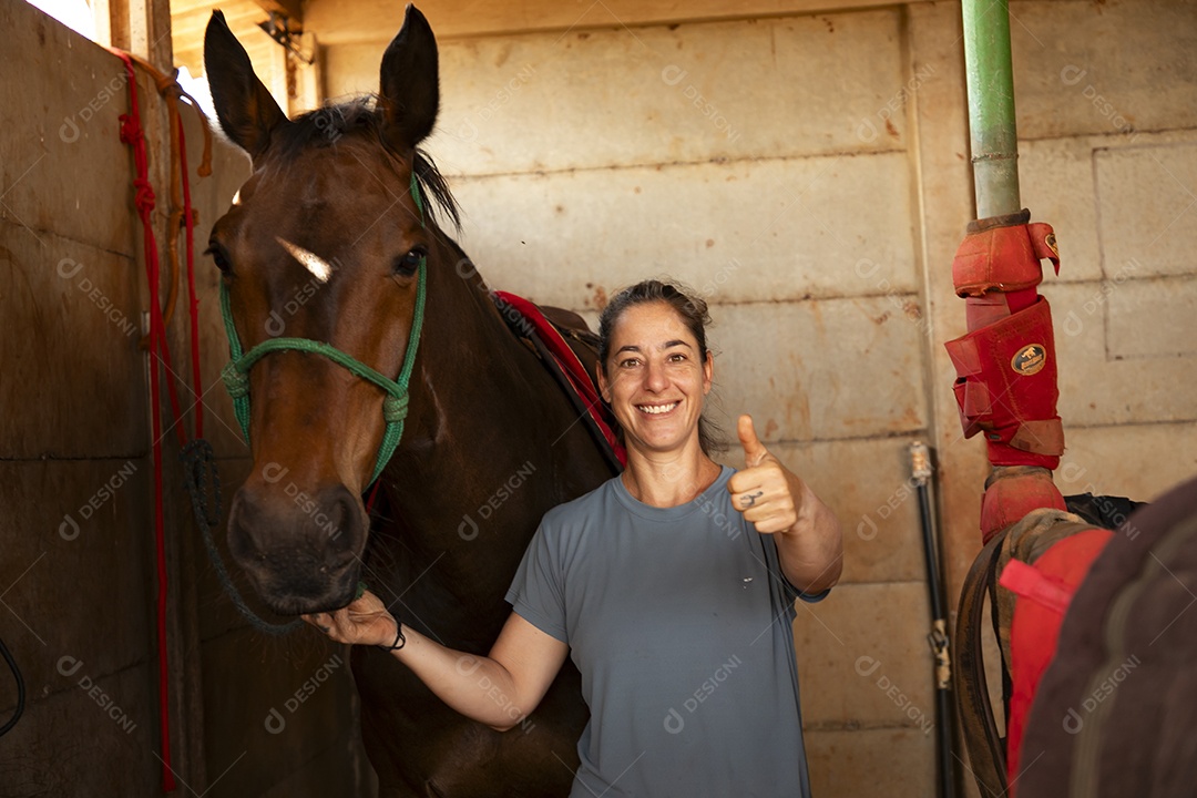 Mulher com gesto de legal segurando rédea de cavalo