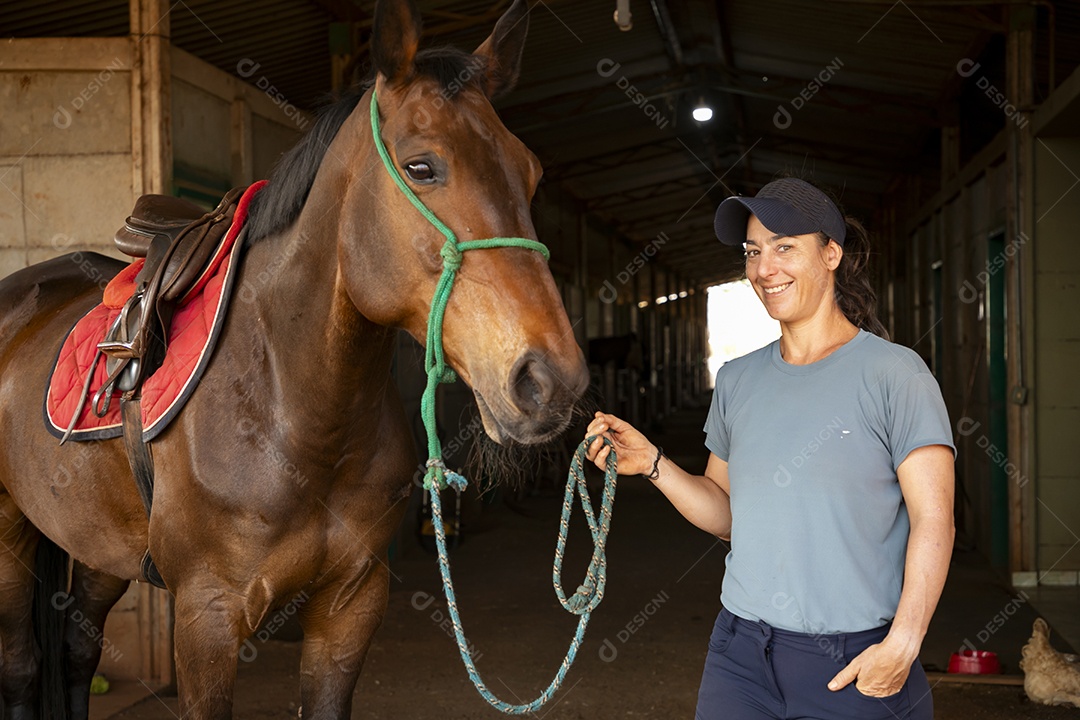 Cavalo selado e mulher segurando nas rédeas