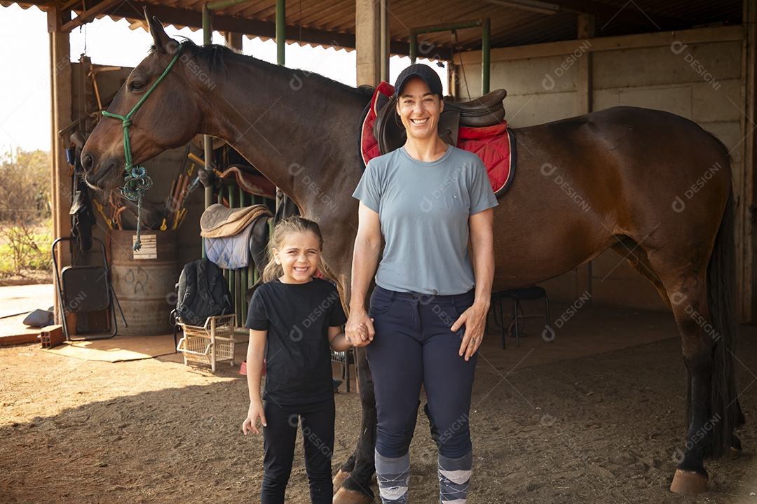 Duas garotas amazonas de mãos dadas e um cavalo atrás