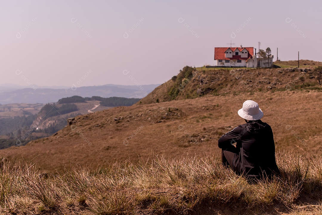 Homem sentado no topo da montanha observando a vista