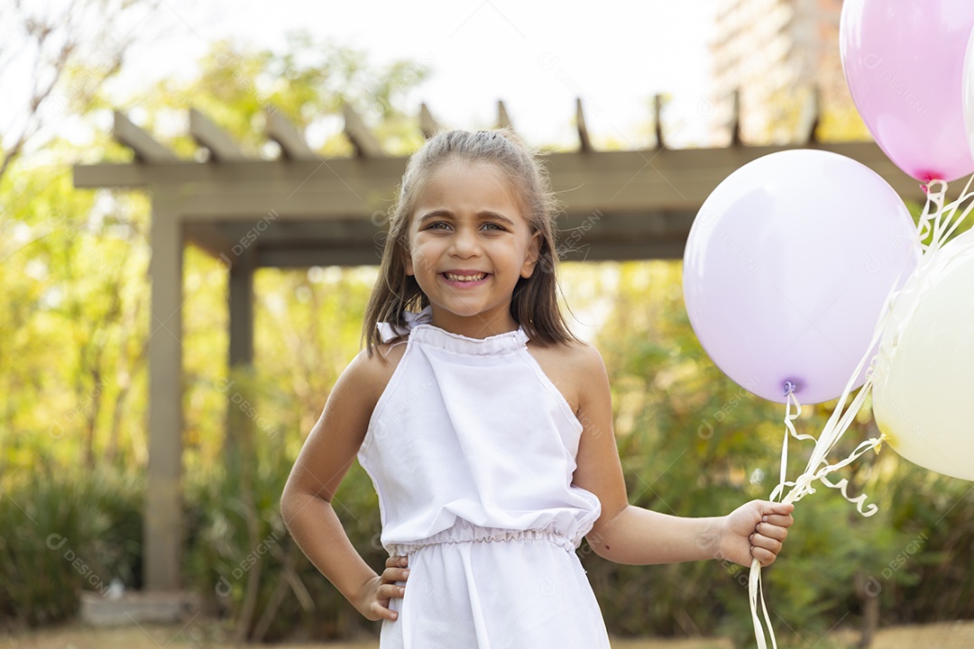 Uma linda garotinha vestida de branco com balões na mão