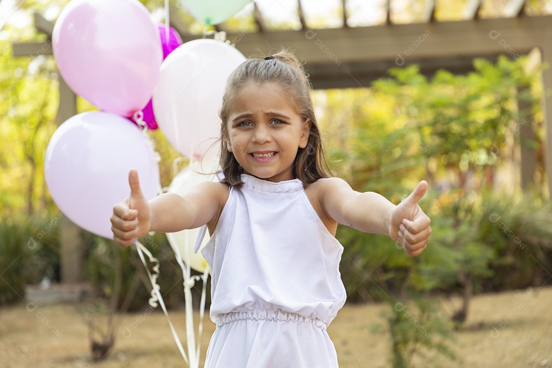 Linda garotinha com gesto de beleza e segurando balões