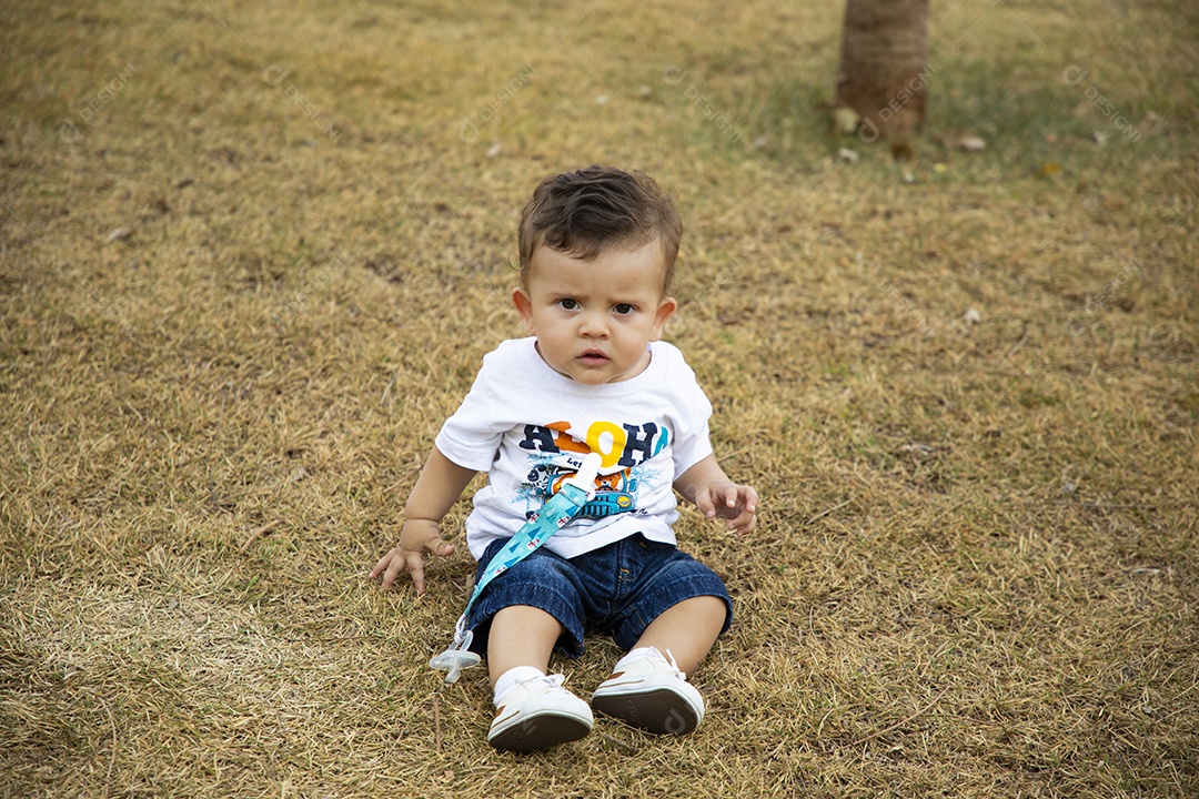 Bebê lindo sentado na grama de um parque
