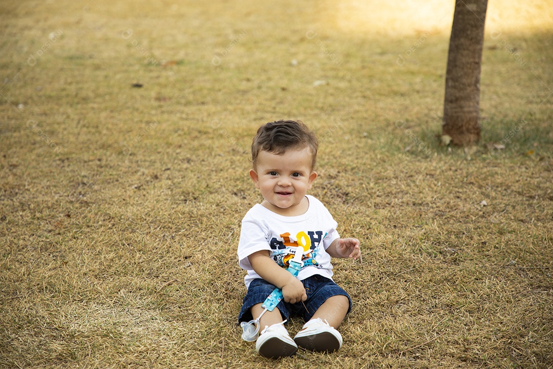 Um lindo neném sentado na grama de um parque