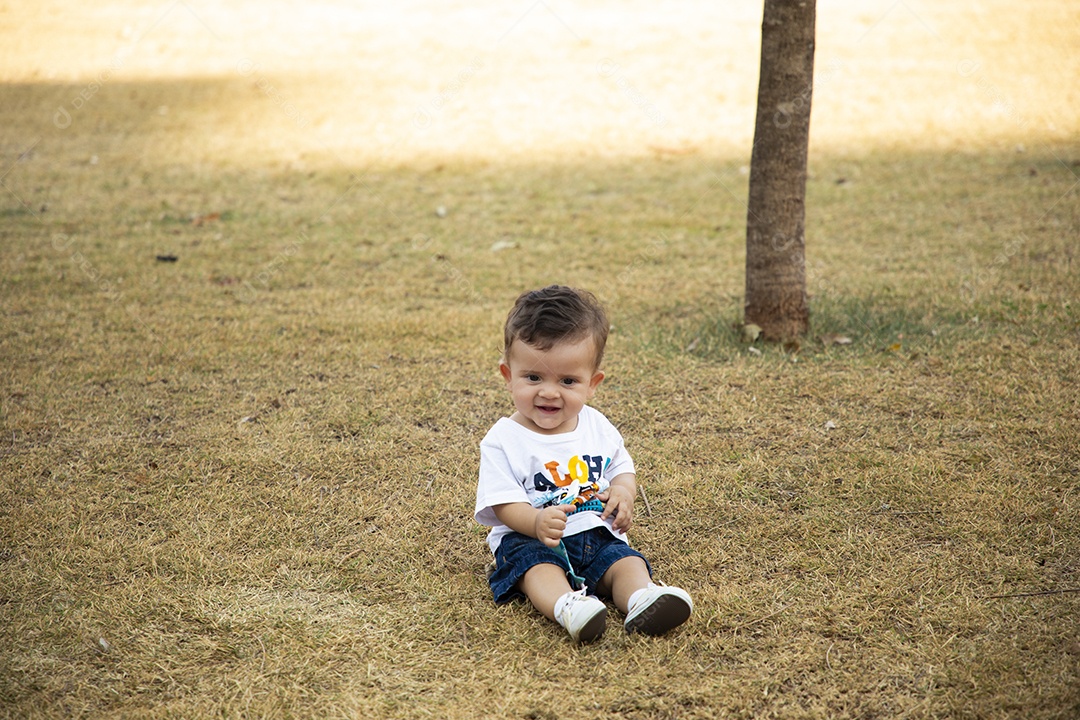 Um lindo neném sentado na grama de um parque