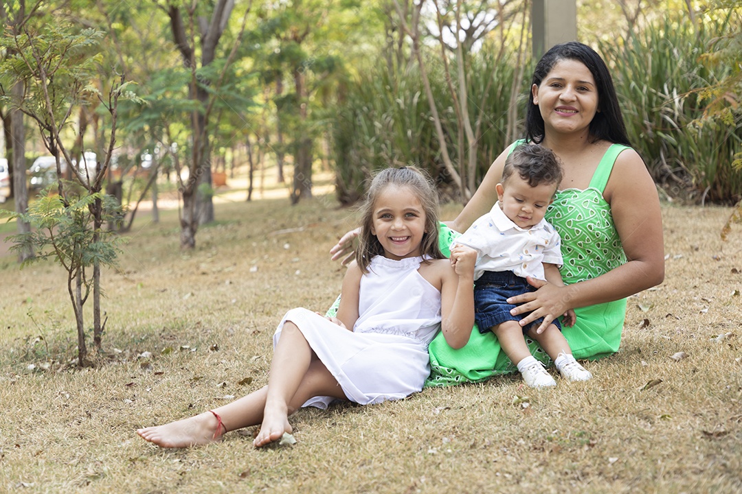 Uma mãe com seus filhos lindo em um parque felizes