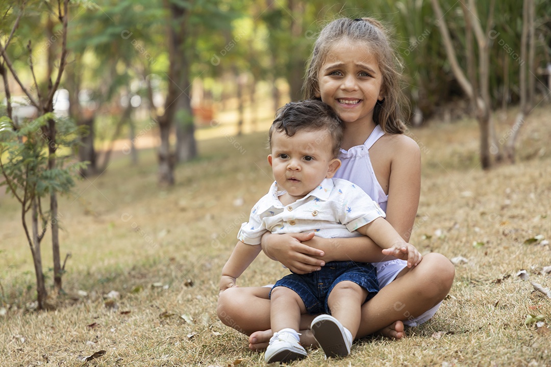 Um lindo bebê no colo da sua irmãzinha