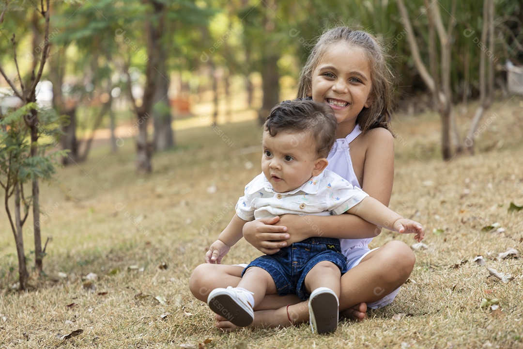 Uma menininha linda segurando seu irmãozinho