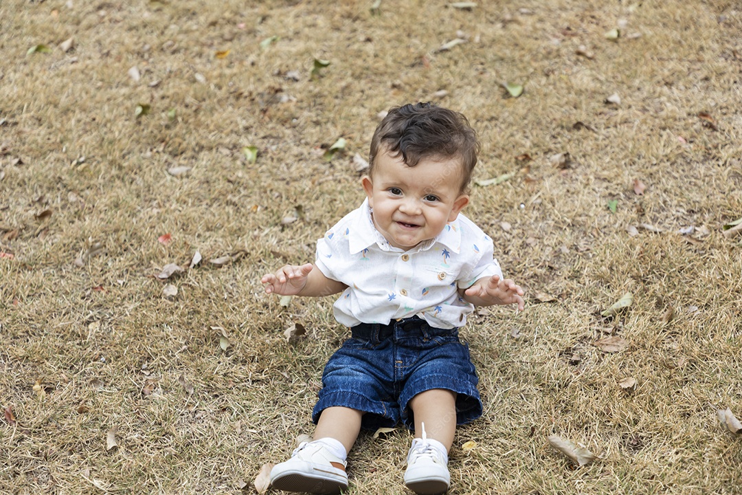 Um neném fofo sentado na grama de um parque