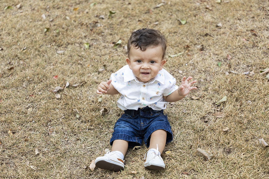 Um neném fofo sentado na grama de um parque