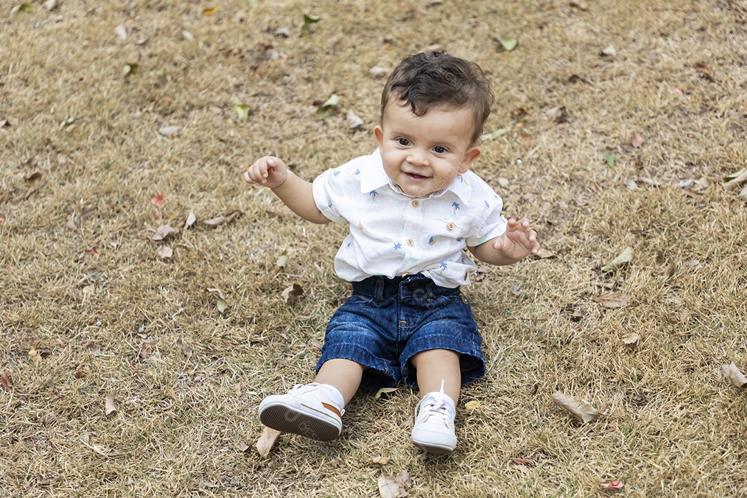 Um garotinho fofo sentado numa grama
