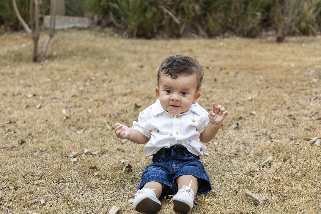 Um bebê fofo sentado na grama de um parque
