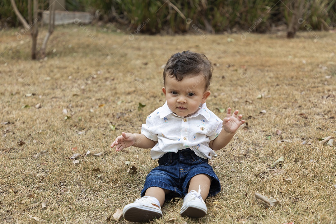 Um neném fofo sentado na grama de um parque