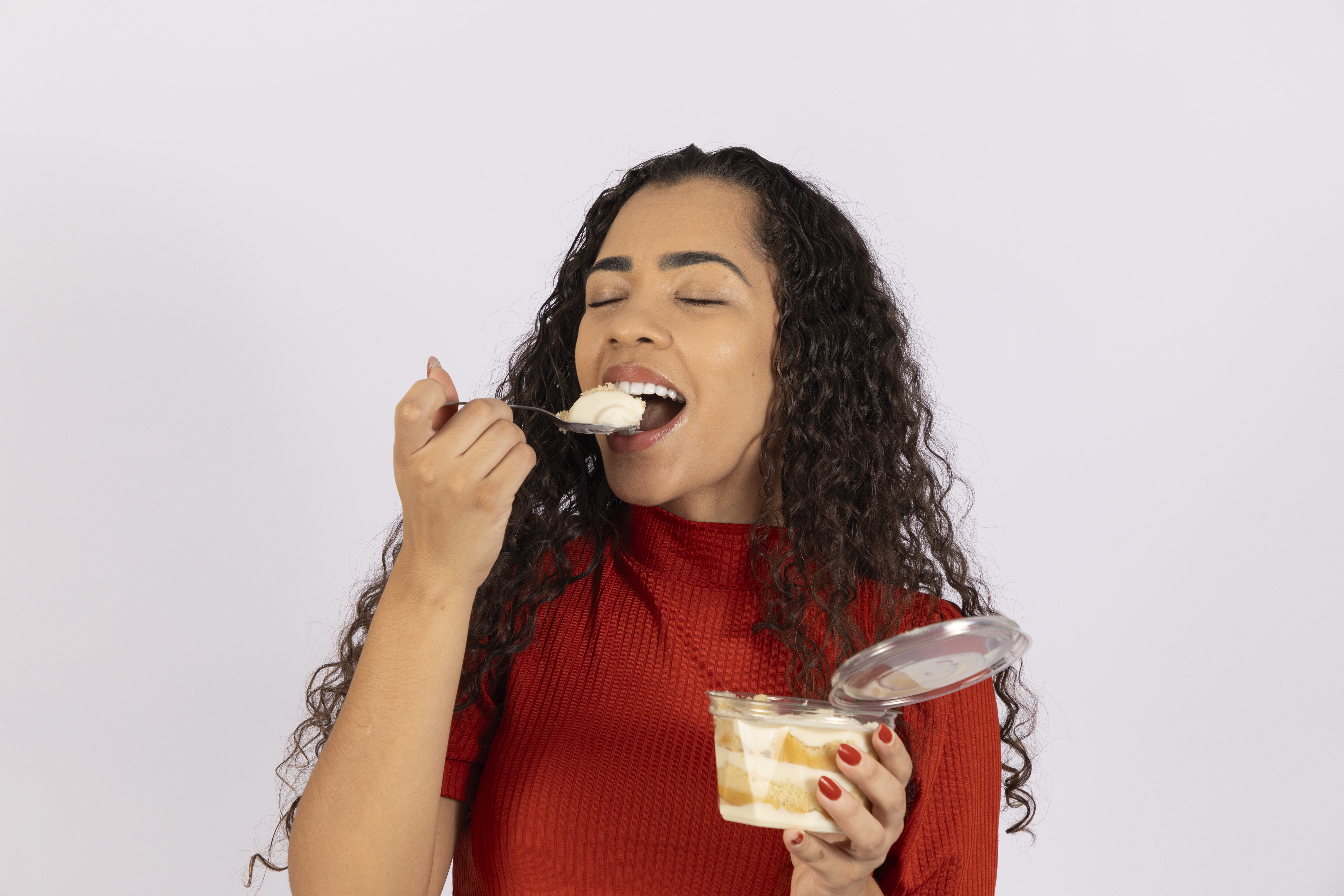 Jovem se deliciando comendo bolo de pote