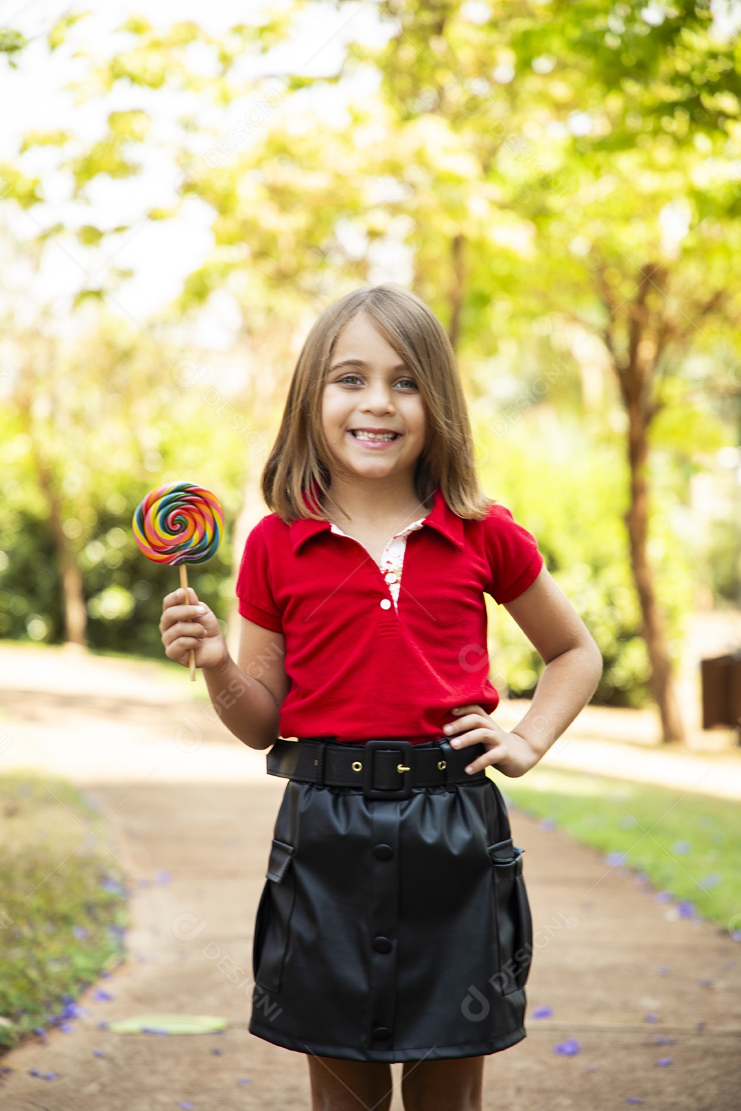 Menina fofa sorrindo com mãos na cintura e um pirulito