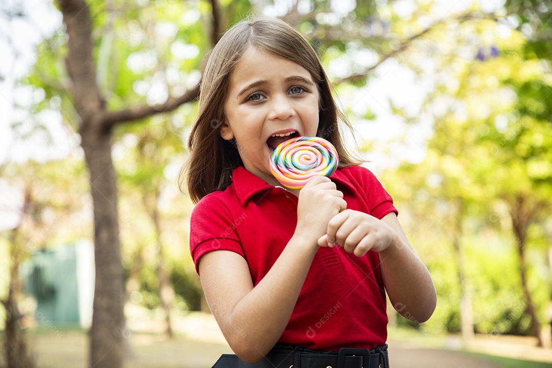 Uma menina fofa com pose e segurando um pirulito