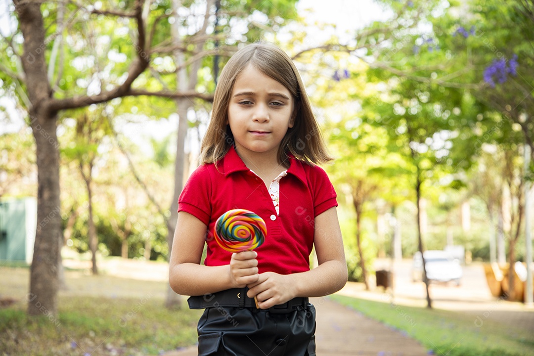Uma menina fofa com pose e segurando um pirulito