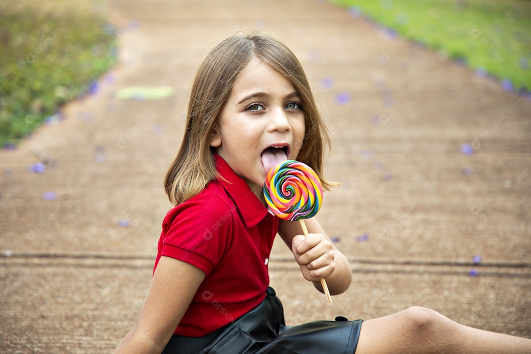 Linda menina loira sentada com seu pirulito