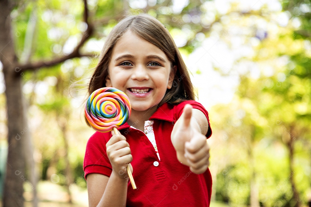 Uma menina linda com pirulito e gesto de legal