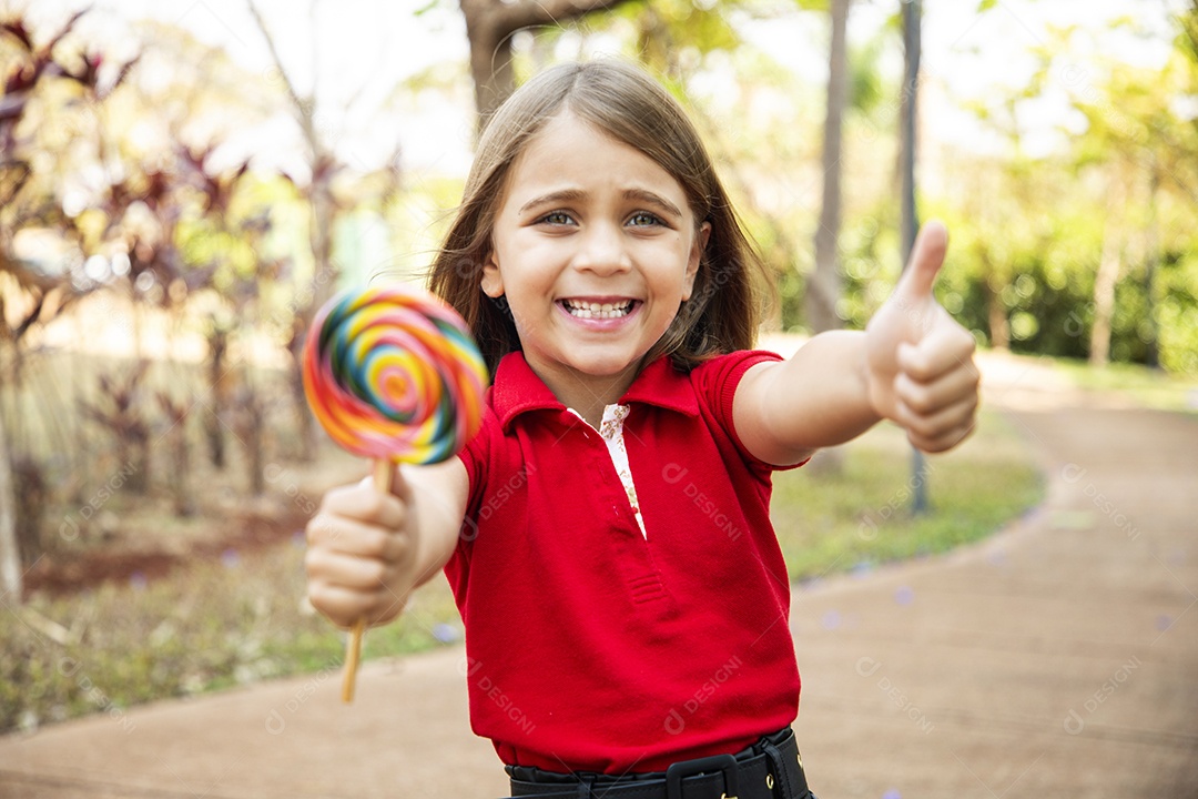 Linda garotinha feliz com seu pirulito e gesto de beleza