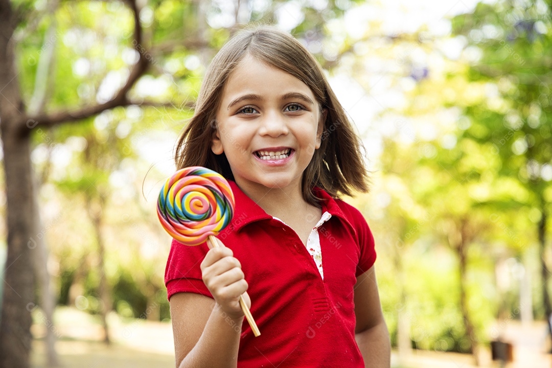 Uma criança fofa sorrindo com pirulito nas mãos